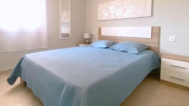 Ein Schlafzimmer mit einem Bett, Nachttischen, einem Spiegel und einem an der Wand hängenden Kunstwerk.