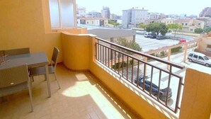 Ein Balkon mit Tisch und Stühlen, Blick auf einen Parkplatz und Gebäude im Hintergrund.