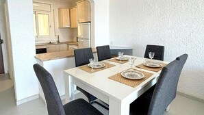 A dining area with a white table set for four, surrounded by dark chairs. - Beautiful apartment in Roses with terrace and garage, 600m from the beach (Roses)