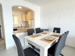 A dining area with a white table set for four, surrounded by dark chairs. - Beautiful apartment in Roses with terrace and garage, 600m from the beach (Roses)