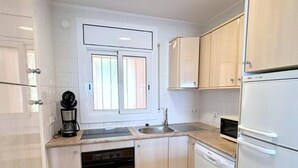 A modern kitchen with white cabinets, a built-in oven, a dishwasher, and a coffee maker. - Beautiful apartment in Roses with terrace and garage, 600m from the beach (Roses)
