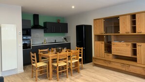 A modern kitchen with a dining area, wooden cabinets, and a built-in oven. - Charming 3-Room Apartment with South Terrace (Chamrousse)