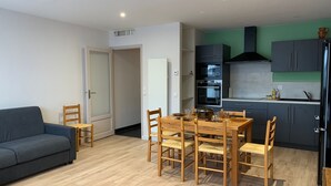 A compact living space with a dining area, kitchenette, and a sofa. - Charming 3-Room Apartment with South Terrace (Chamrousse)