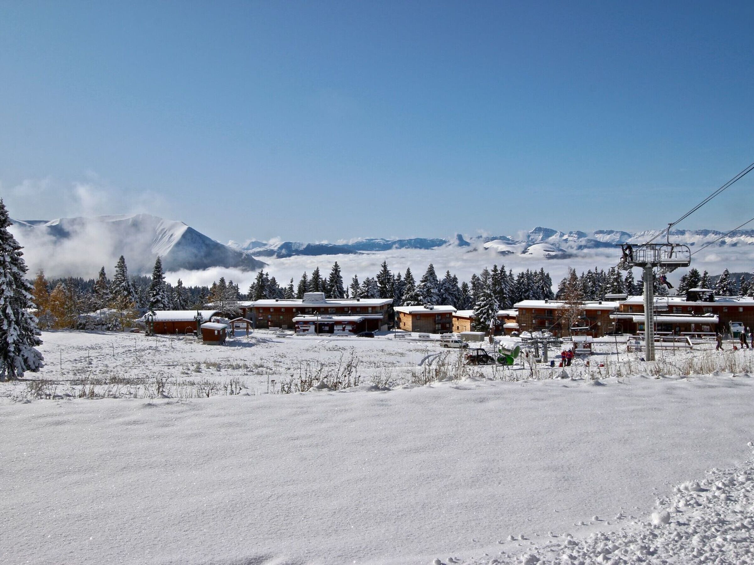 A snow-covered mountain resort with wooden cabins and a ski lift.