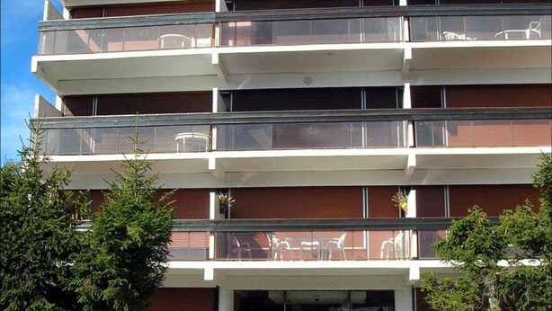 A multi-story building with balconies, each with a glass railing. - Charming 3-Room Apartment with South Terrace (Chamrousse)