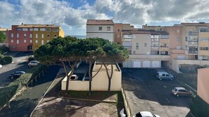 Zona residencial con edificios de varios pisos, un estacionamiento y un camino bordeado de árboles.