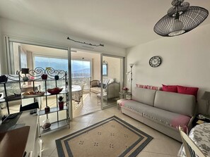 Una sala de estar con sofá, una mesa de comedor y un balcón con vistas.