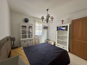 Ein Schlafzimmer mit einem Bett, einem Kleiderschrank, einem Fernseher und einer Tür.