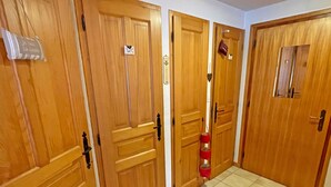 Ein Flur mit Holztüren, einem WC-Schild und einem roten Feuerlöscher.