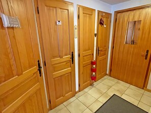 Ein Flur mit Holztüren, einem WC-Schild und einem roten Feuerlöscher.