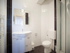 Et moderne badeværelse med hvid vask, spejl og toilet.