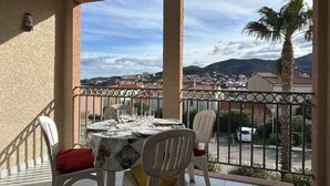 Un balcon avec une table dressée pour le dîner, offrant une vue sur la ville et les collines.