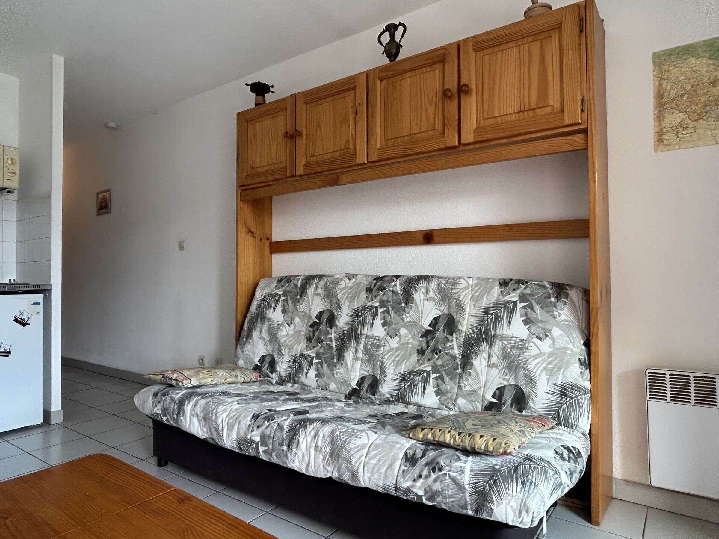 Een woonkamer met een bank, houten kasten en een betegelde vloer.