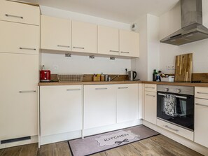 Eine Küche mit weißen Schränken, einer Holz Arbeitsplatte, einer Edelstahl-Dunstabzugshaube und einem schwarzen Backofen.