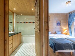 Ein Holzblockhaus-Interieur mit Badezimmer, Bett und Nachttisch.
