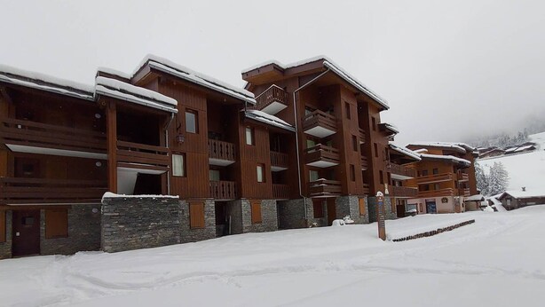 A multi-story wooden lodge with balconies, set against a snowy backdrop. - Cozy Studio on the Slopes - Sleeps 4 (Valmorel)