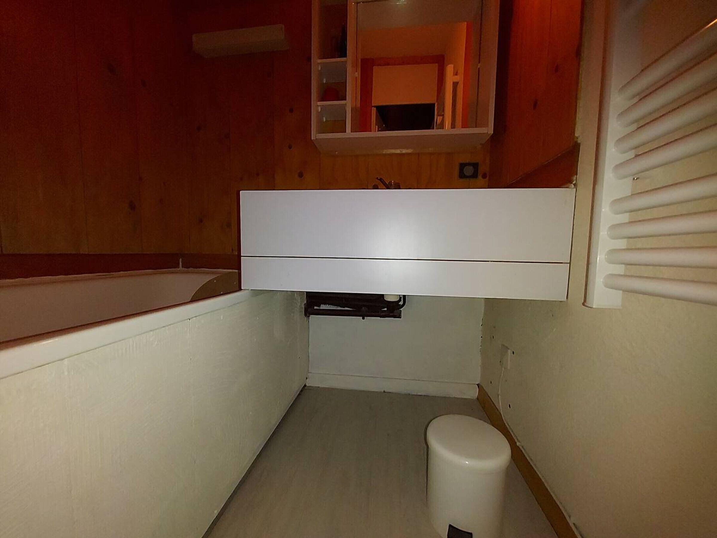 A small, narrow bathroom with a white sink, a toilet, and a mirror above the sink.