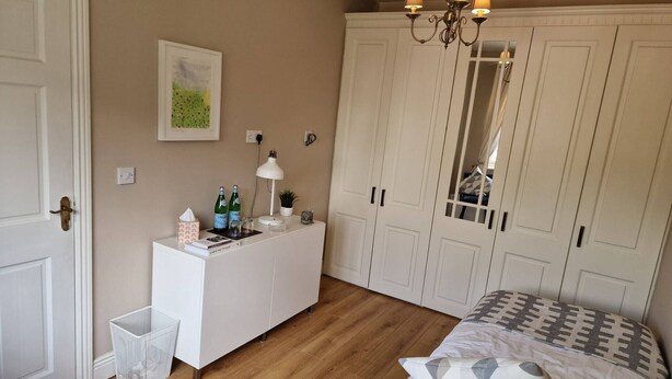 A bedroom with a bed, a dresser, a mirror, and a chandelier. - Room-walkinstown Retreat House (Dublin)
