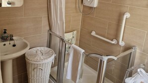 A modern bathroom with a glass shower enclosure, a white sink, and a wicker basket. - Room-walkinstown Retreat House (Dublin)