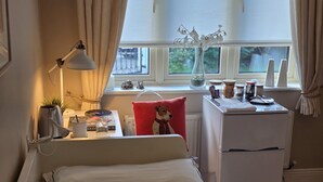 A bedroom with a bed, a desk, a radiator, a window with curtains, and a vase with flowers. - Room-walkinstown Retreat House (Dublin)