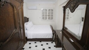 A bedroom with a bed, a wardrobe, a mirror, and a window with shutters. - seaview hotel (Alexandria)