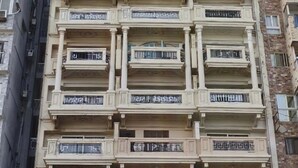 A multi-story building with balconies, a storefront at the ground level, and a clear sky above. - seaview hotel (Alexandria)