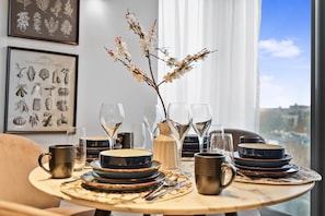 A dining table set with plates, glasses, and a vase with flowers. - Comfortable & Peaceful 2BR Apartment Near King’s Cross (London)