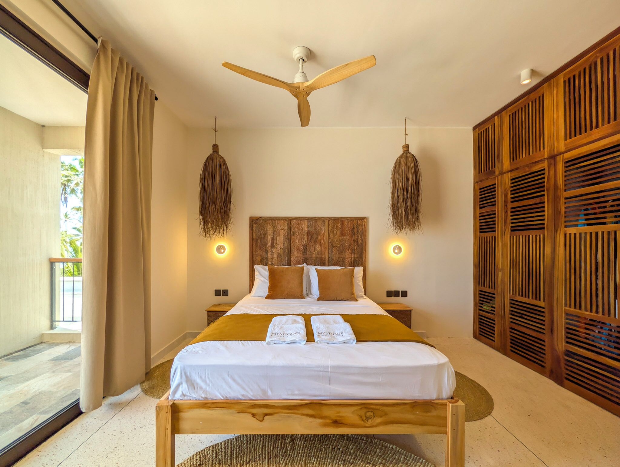 A spacious bedroom with a large bed, wooden headboard, and a ceiling fan.