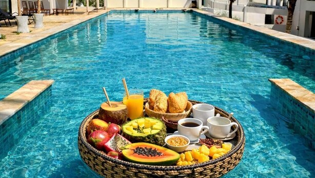 Une piscine avec un plateau flottant rempli d’aliments pour le petit-déjeuner.