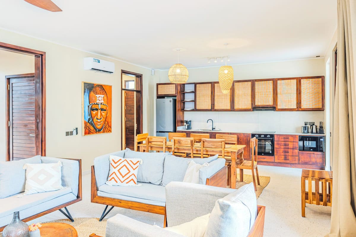 Ein modernes Wohnzimmer mit einer Couch, Sesseln und einer Essecke mit Holzkunst.