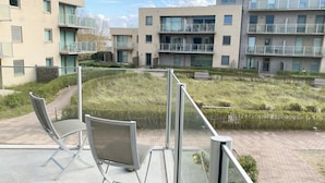 Un moderno complejo de apartamentos con varios balcones, un patio central con césped y un sendero pavimentado.