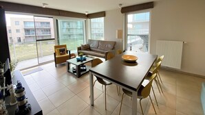 Un salón amplio con sofá, una mesa de comedor y sillas. Una ventana grande ofrece vistas al exterior.