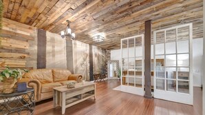 A room with a wooden ceiling, a leather sofa, a wooden coffee table, and a large window with a view. - Swann Ave Suite Walk to Bayshore Hyde Park (Tampa)