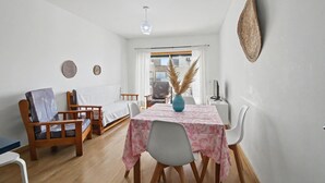 A room with a bed, a dining table with chairs, a blue vase, and a hanging light fixture. - Apartment 'Ocean Terrace 3 B - With Pool' with Swimming Pool and Balcony (Armação de Pêra)