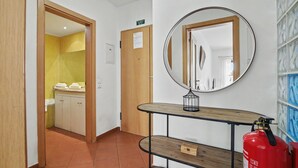 A hallway with a wooden door, a mirror, a fire extinguisher, and a tiled wall. - Apartment 'Ocean Terrace 3 B - With Pool' with Swimming Pool and Balcony (Armação de Pêra)