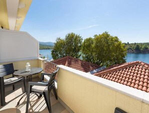 A balcony with a table and chairs, overlooking a lake and trees. - 1-bedroom Sea-view Apartment in Obrovac (Obrovac)