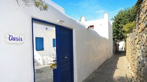 Uma rua estreita com um prédio branco e uma porta azul com a inscrição 'Oasis'.