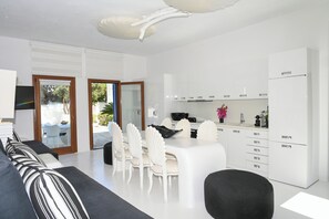 Eine moderne Küche mit weißen Schränken und einem Essbereich mit einem weißen Tisch und Stühlen.