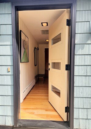 A hallway with a wooden floor, beige walls, and a door with multiple windows. - Lenox Interlude Stylish Retreat Walk to Town  (Lenox)