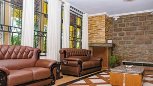 A living room with two brown leather sofas, a coffee table, and a fireplace. - Casa Kalimbini Resort (Sultan Hamud)