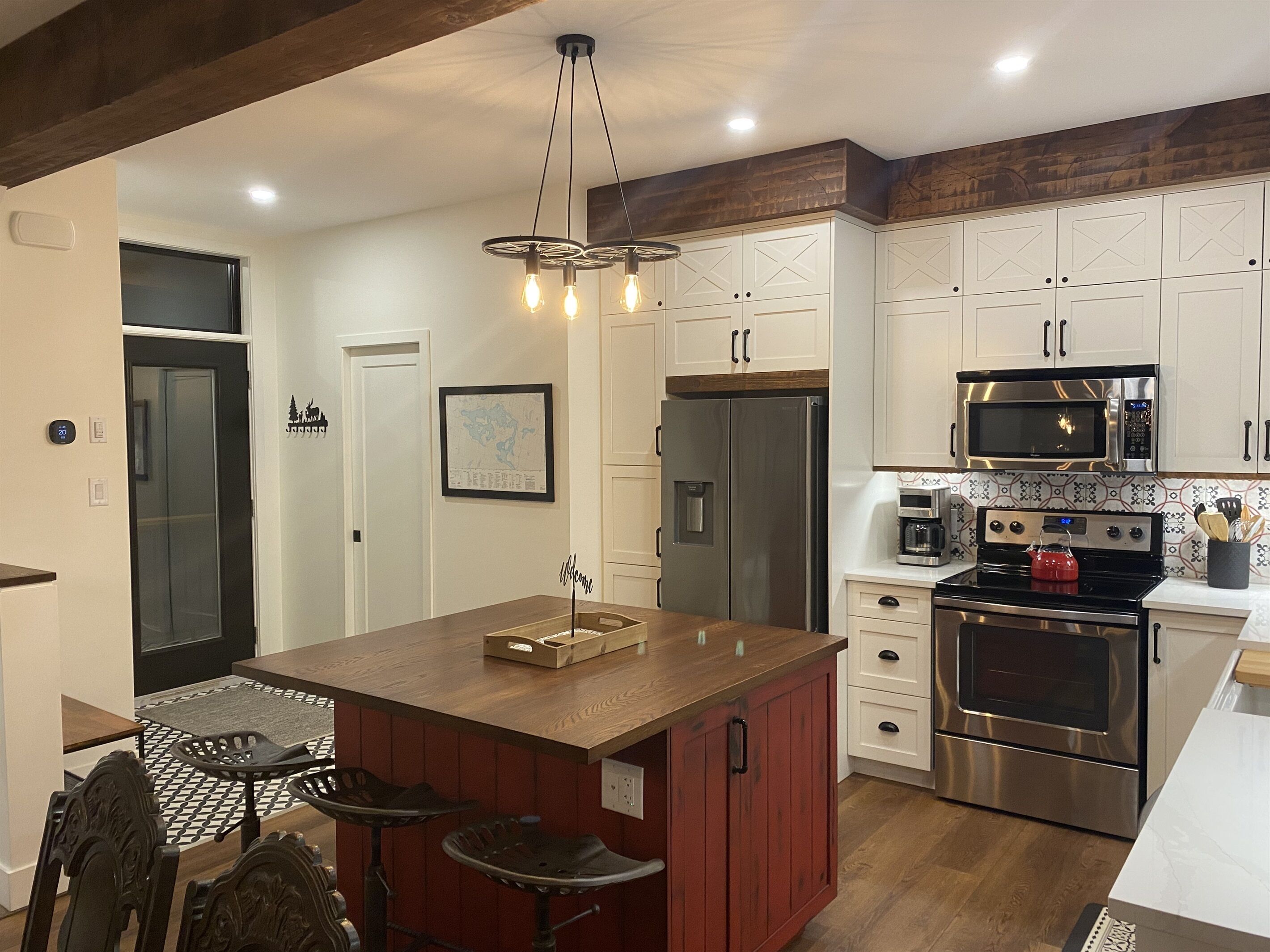A modern kitchen with a central island, stainless steel appliances, and a wooden ceiling.