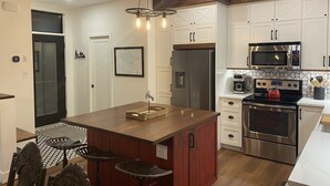 Une cuisine moderne dotée d’un îlot central, d’appareils électroménagers en acier inoxydable et d’un plafond en bois.