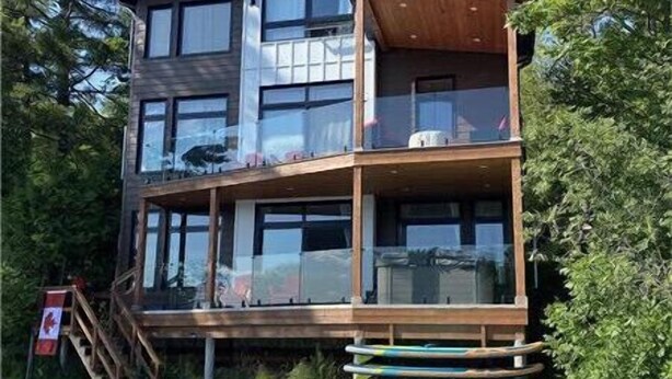 Un immeuble à plusieurs étages doté d’une terrasse en bois, d’un quai et d’une chaise.