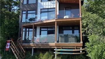 A multi-story building with a wooden deck, a dock, and a chair.