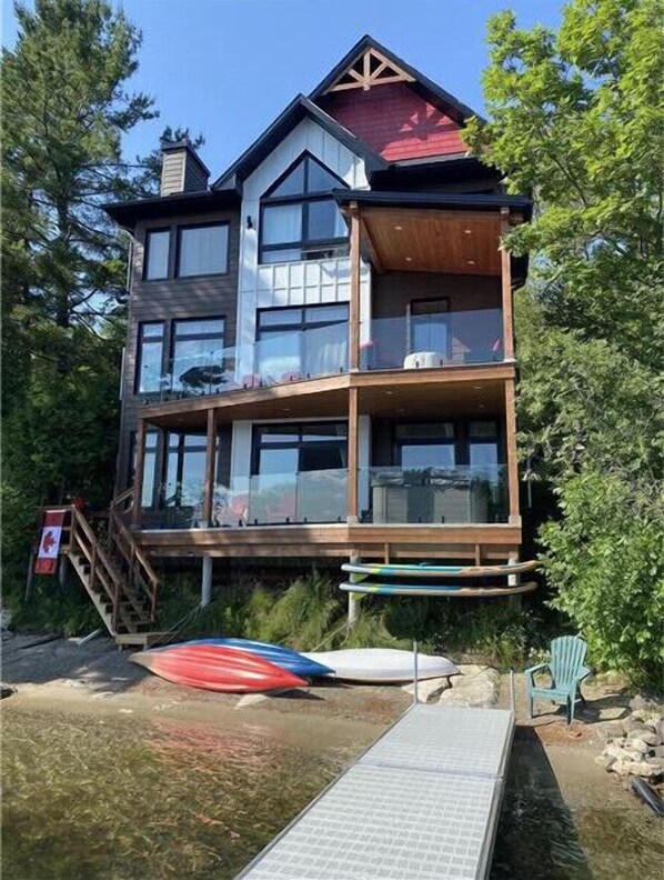 A multi-story building with a wooden deck, a dock, and a chair.