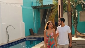 A swimming pool with a tiled edge, a concrete deck, and a palm tree.