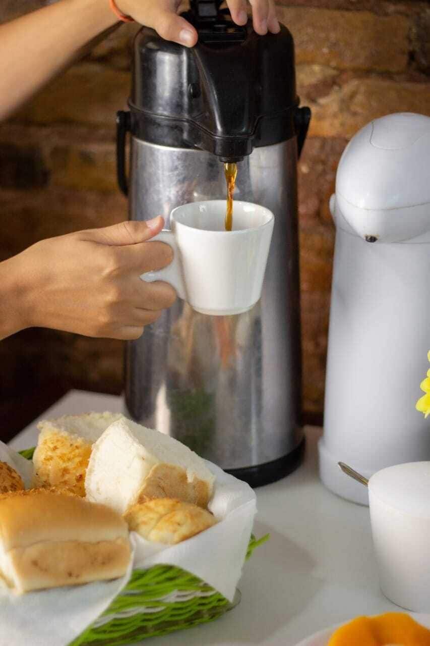 A person pouring coffee from a coffee press into a cup.