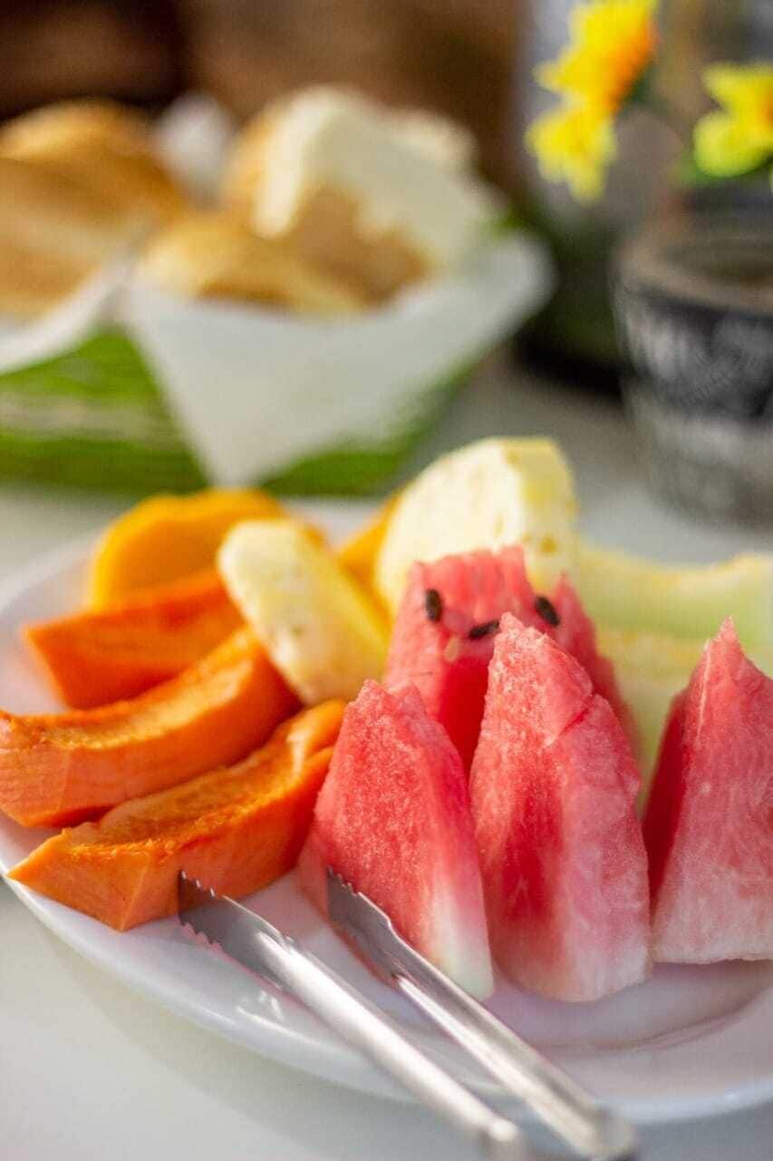 A plate with sliced fruits and a knife.