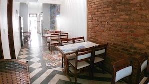 A dining area with a brick wall, a checkered floor, and wooden furniture.