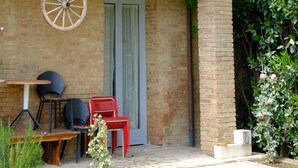 Un edificio r ústico con un balcón, una mesa de madera y sillas rojas.